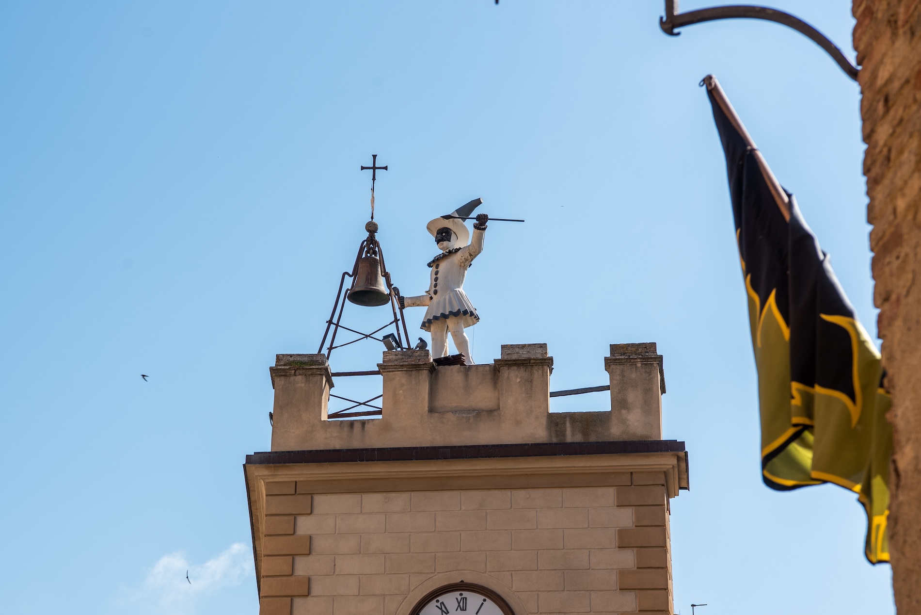 Wie omhoog kijkt, ziet ergens ook een wit mannetje op het dak staan met een Zorro-achtig masker. Het is Pulcinella, een figuur uit het Italiaanse theater.