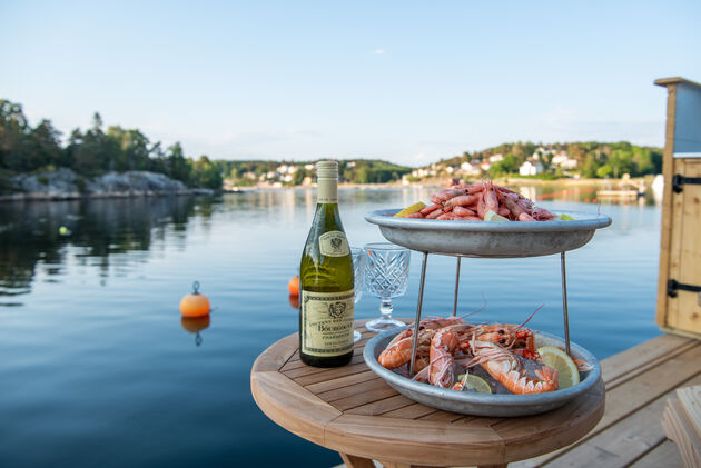 Een typisch Zweeds diner met verse garnalen, brood, sausjes en een fles witte wijn